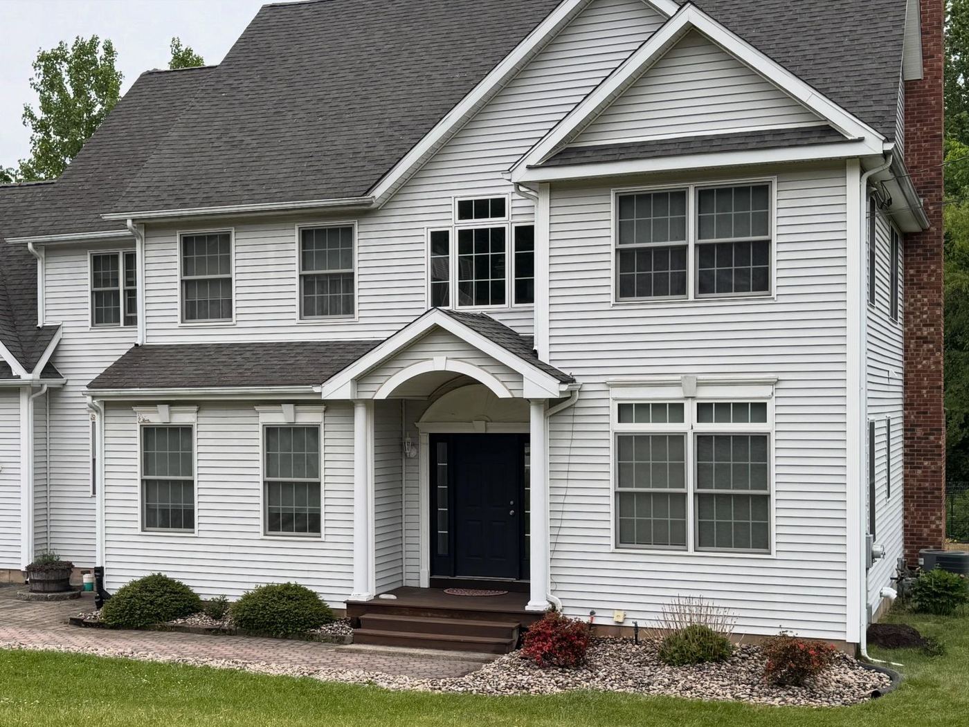 White colonial with fresh mulch beds and trimmed shrubs, cared for by Iovanna
